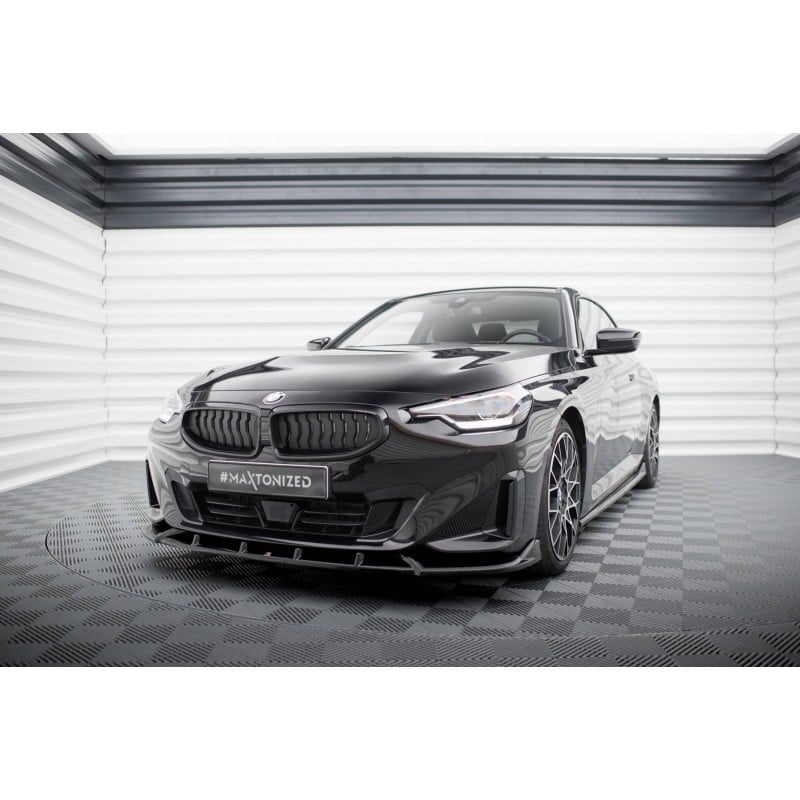 Voiture noire BMW dans un showroom, vue frontale droite sur le capot et le spoiler avant.