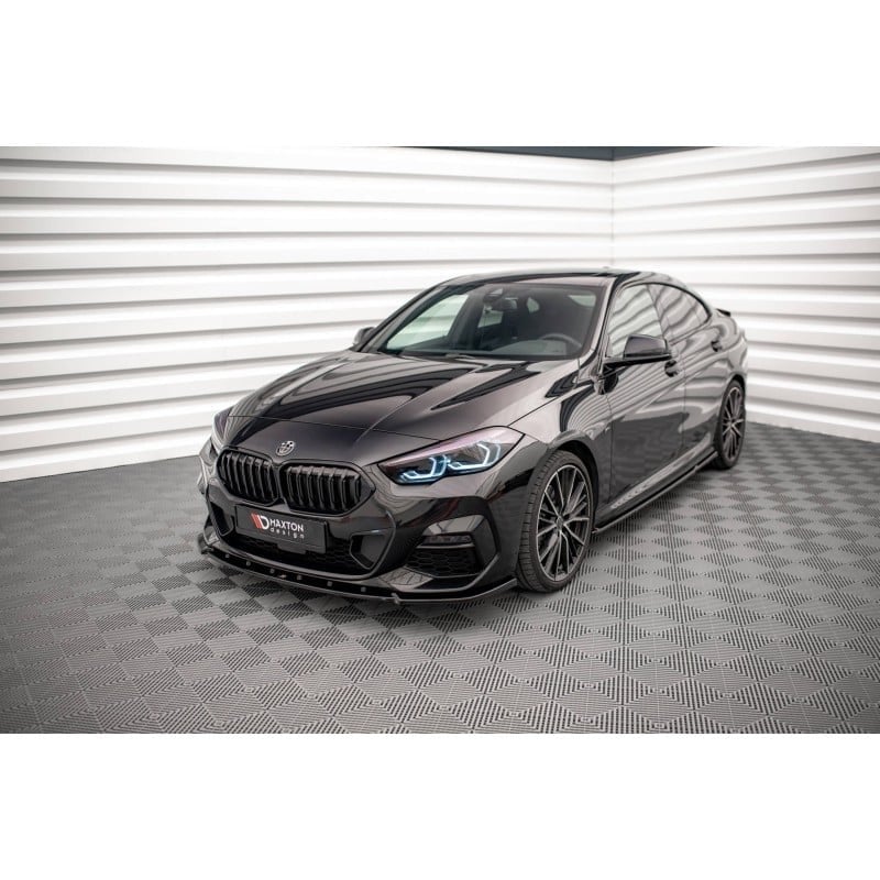 Voiture sportive noire vue de trois-quarts avant dans un studio, avec feux bleu et calandre sportive.